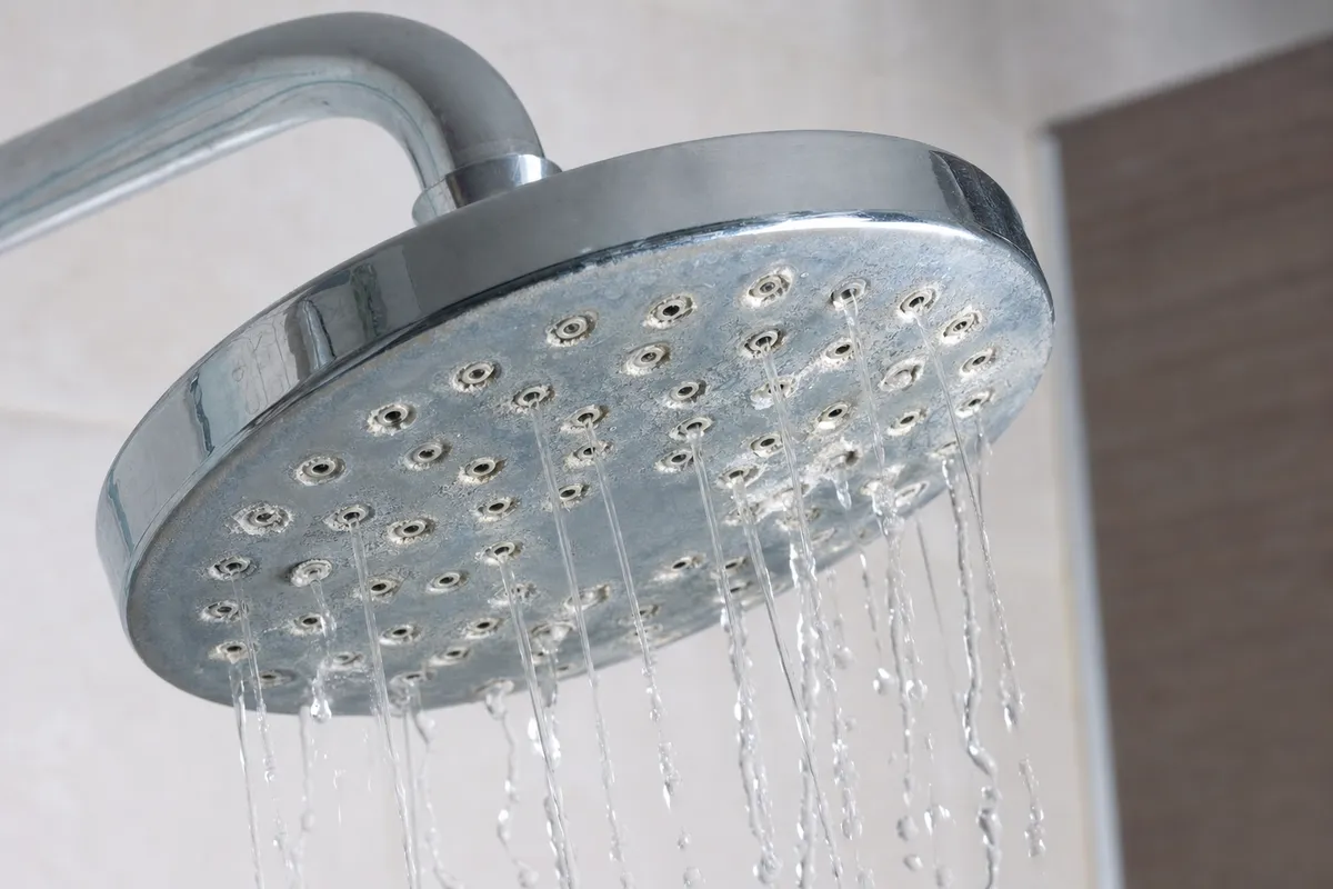 Soffione doccia cromato con incrostazioni di calcare e getto d’acqua debole e irregolare