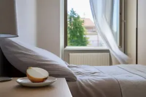 Mezza cipolla su un piattino sul comodino, con letto e finestra aperta sullo sfondo