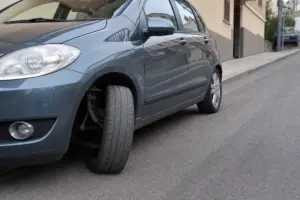 Auto grigia parcheggiata in salita con ruota anteriore sterzata al massimo verso il marciapiede