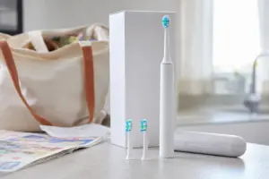 Kit con spazzolino elettrico bianco, due testine di ricambio, custodia e scatola neutra su un piano
