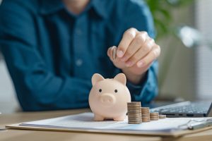 retirement, earnings, financial, loan, economic, finance, wealth, piggy bank, assurance, future. A person is putting coins into a piggy bank. Concept of saving money and being financially responsible.