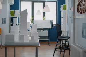 Empty technical office with real estate construction plan and building model on desk. Nobody in workplace used for construction design and architectural structure with urban project.