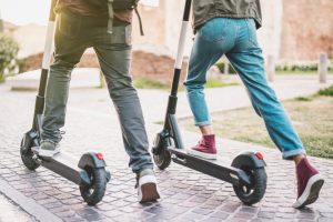 Close up of people couple using electric scooter in city park - Millenial students riding new modern ecological mean of transport - Green eco energy concept with zero emission - Warm sunshine filter