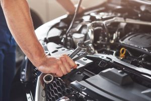 Picture showing muscular car service worker repairing vehicle.