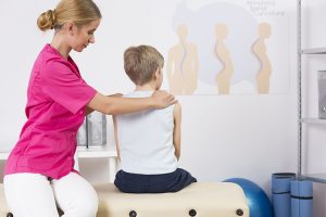 Physiotherapist correcting body posture of a small boy