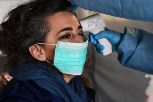 A nurse controls the temperature of a woman in the a pre-triage medical tent in front of the Cremona hospital, in Cremona, northern Italy, on March 4, 2020. - Italy will recommend people stop kissing in public, avoid shaking hands and keep a safe distance from each other to limit the spread of the novel coronavirus. Other measures to be approved by the government, which has borne the brunt of the COVID-19 disease, includes a plan to play all football matches behind closed doors. (Photo by Miguel MEDINA / AFP)